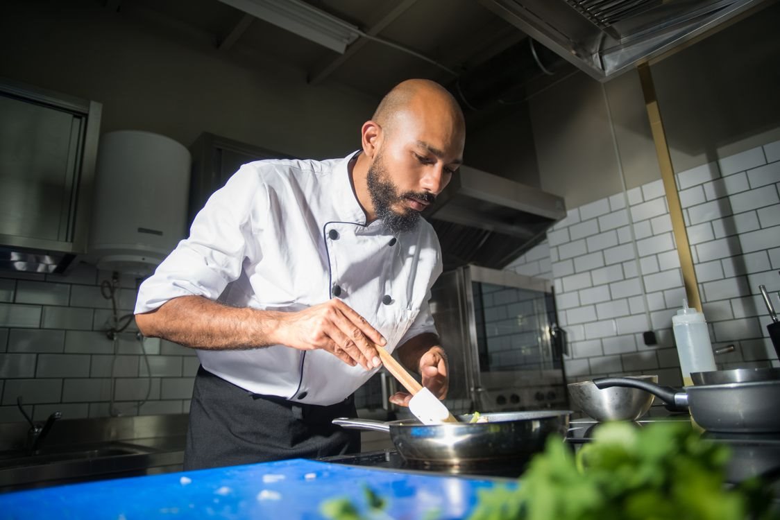 Chef preparing a dish in the Tāstra kitchen